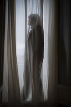 Woman standing behind a curtain