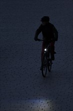 The silhouette of a cyclist with lights looms in Berlin