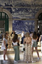 Young female tourist looking at the azulejos at Porto Sao Bento station