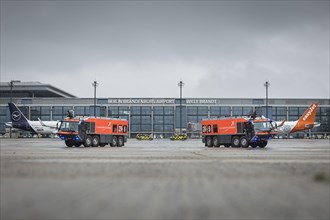 Two vehicles of the airport fire brigade drive across the tarmac during the opening of Terminal 1 at Berlin Brandenburg Willy Brandt Airport