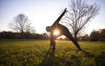 Man stretching in a meadow in autumn. Gymnastics outdoors.