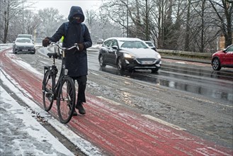 Cyclist walking on foot holding bicycle on slippery bike path