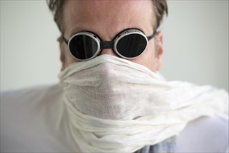 Man with sunglasses and a scarf cover his face