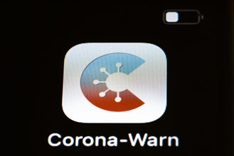 The Corona warning app is displayed on the screen of a smartphone. The app is designed to help trace and interrupt chains of infection of SARS-CoV-2