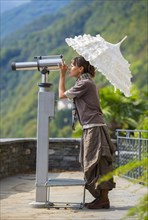 Woman with an umbrella using a telescope