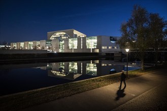 A person stands out in front of the Federal Chancellery at blue hour