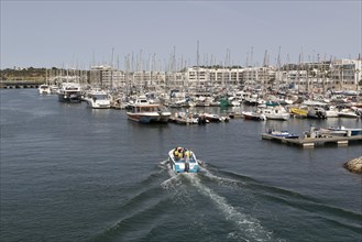 Tour boat with tourists and sailing boats in the marina of Lagos