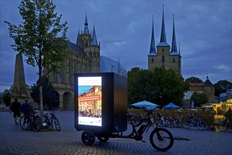 Illuminated advertising on cargo bike on the cathedral square in the evening