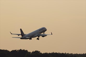 Passenger aircraft Embraer 190 of the airline Airfrance taking off into the evening sky at Hamburg Airport