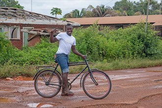 Local cyclist riding along muddy dirt road in the village Lethem during the rainy season