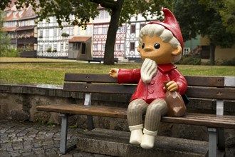 Sculpture of the Sandman on a bench in front of half-timbered houses on Kraemerbruecke in Erfurt