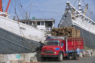 Truck loaded with timber in front of wooden pinisis