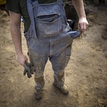 Dirty and tattered overalls of a construction worker. A construction worker shakes soil out of his empty trouser pocket. Berlin