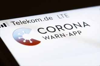 The Corona warning app is displayed on the screen of a smartphone. The app is designed to help trace and interrupt chains of infection of SARS-CoV-2