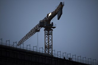 Construction workers draw on scaffolding in front of a construction crane in Berlin