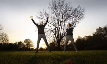 Man and woman doing early morning exercise in a meadow in autumn.