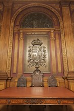 Wood-panelled wall with coat of arms of the Portuens Chamber of Commerce 1889