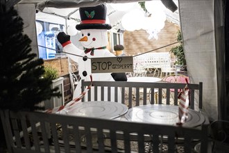 A sign reading 'Stop Gesperrt!' stands next to an inflatable snowman at a cafe in Berlin