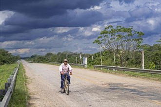 Elderly Bolivian man riding on bicycle along road Ruta Nacional 9