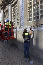Woman restoring facade with azulejos