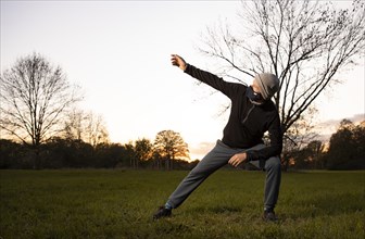 Man with mask stretches in a meadow in autumn.