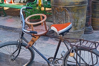 Homemade wooden child's seat mounted on an old rusty bicycle in Cuba