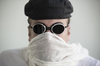 Man with hat and sunglasses and a scarf cover his face
