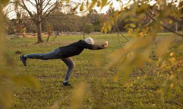 Man stretching in a meadow in autumn. Outdoor sports.