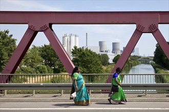 Two woman in traditional saris on their way to the temple festival in front of industry at the Datteln-Hamm canal