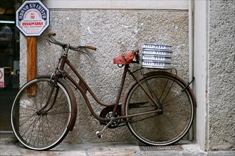 Old bicycle with ensaimada packages on the rack in front of a bakery