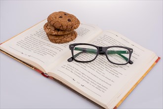 Chocolate chip cookies and glasses placed on a book