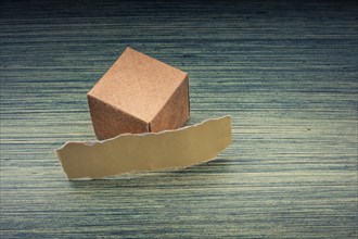 Torn paper and a paper box cube on wooden texture