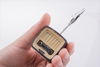 Hand holding a retro TV model on a white background