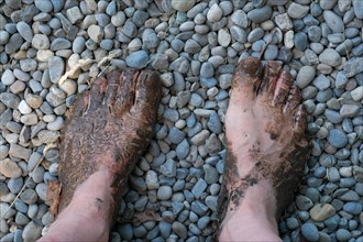 Feet of a man on gravel on the Wuppenau barefoot path on Nollen