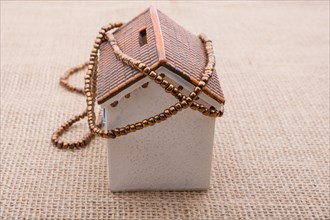 Beads wrapped around a model house on a brown background