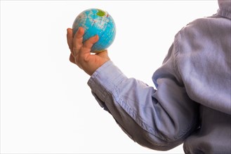 Baby with blue shirt holding a small globe in hand on white background