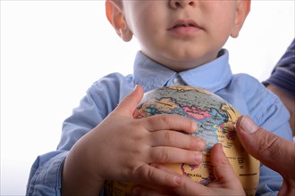 Baby with blue shirt holding a globe in hand on white background