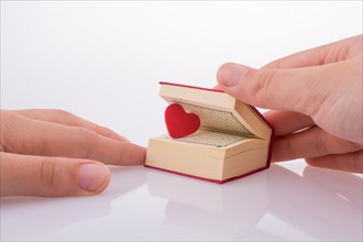 Hand holding The Holy Quran with a heart on a white background
