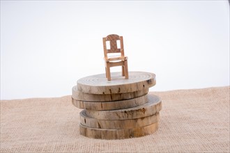 Brown color wooden toy chair on wooden logs on canvas