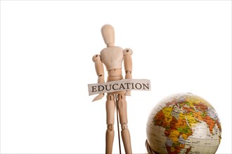 Wooden man holding education sign standing in front of a globe on a white background