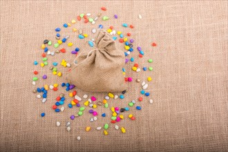 Little sack amid colorful pebbles spread on canvas