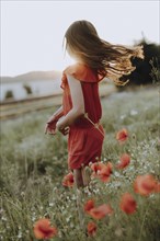 Girl in a red dress in a poppy meadow