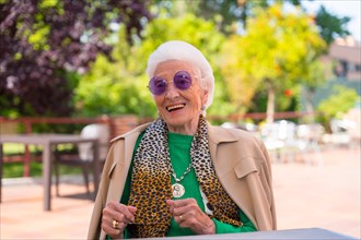 An elderly woman dancing in the garden of a nursing home or retirement home at a summer party wearing sunglasses