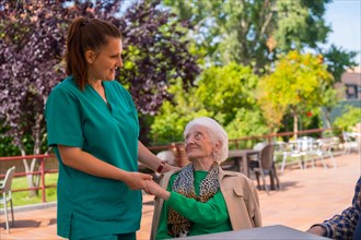An older or mature woman with the nurse in the garden of a nursing home in a moment of affection