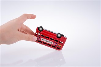 Child hand playing with London double decker bus model on white background