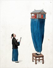 A Chinese puppeteer standing on a stool and balancing a miniature stage above him