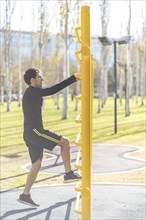Young man doing climbing vertical exercise in the park