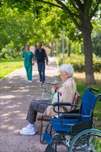 Portrait of an elderly woman sitting on a chair in the garden of a nursing home in a wheelchair