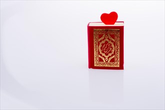 The Holy Quran with a heart on a white background