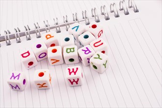 Letter cubes of alphabet of various color on a spiral notebook